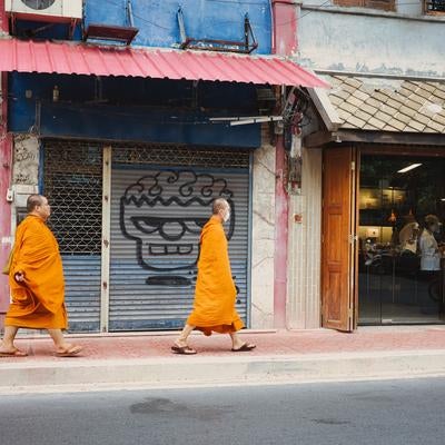 オレンジ色の袈裟をまとい街中を歩く二人の僧侶の写真