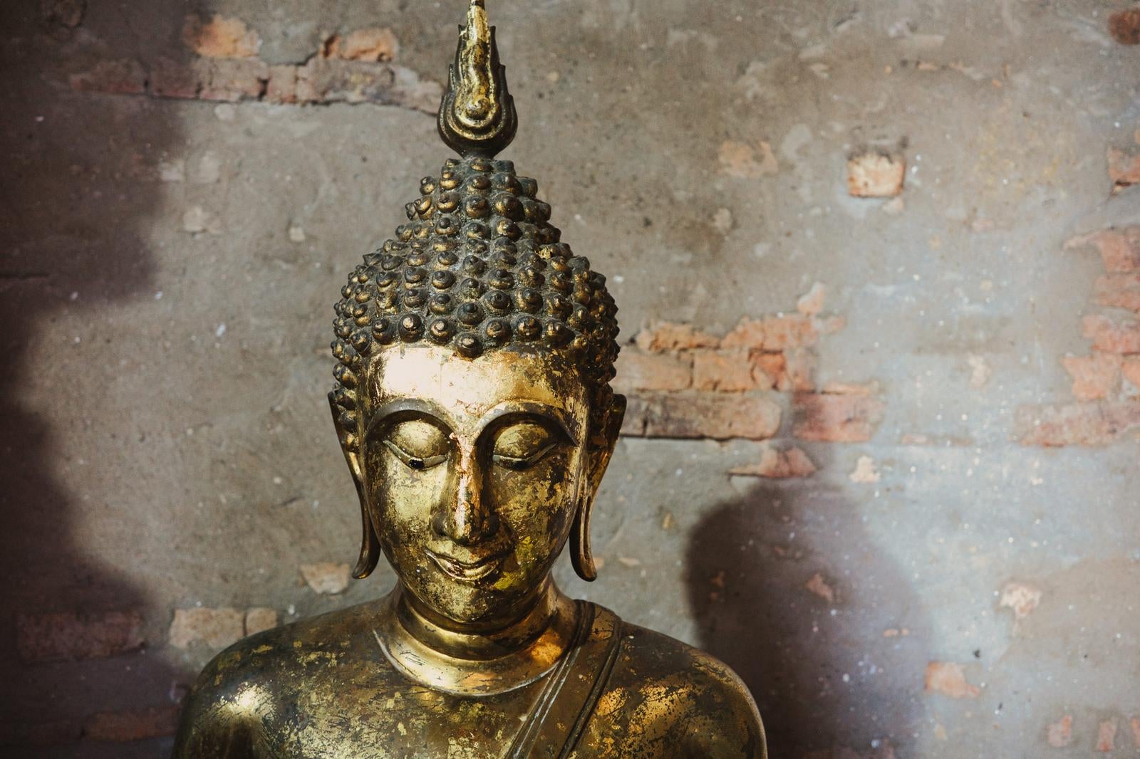 Gilded Buddha Statue Torso in Front of an Old Brick Wall - free stock photo