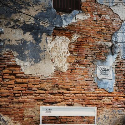 剥がれた塗装の壁面と白いベンチの写真