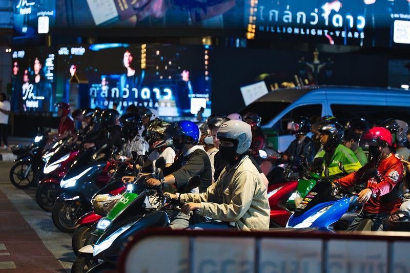 夜の街で信号待ちする多数のスクーターとバイカー