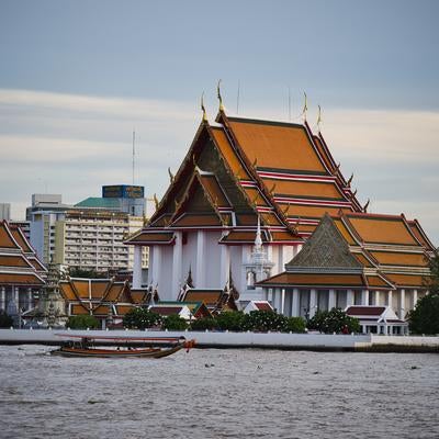 チャオプラヤー川沿いのタイ仏教寺院群と観光船の写真