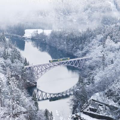 雪化粧した森を渡る列車と第一只見川橋梁の写真