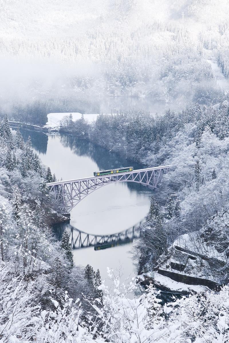 雪化粧した森を渡る列車と第一只見川橋梁の写真