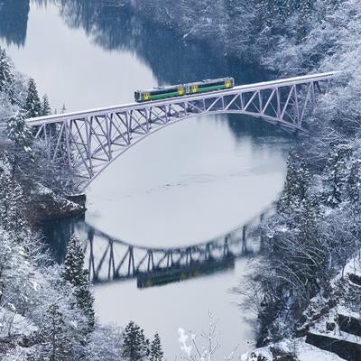 雪に覆われた第一只見川橋梁を走る列車の冬景色の写真