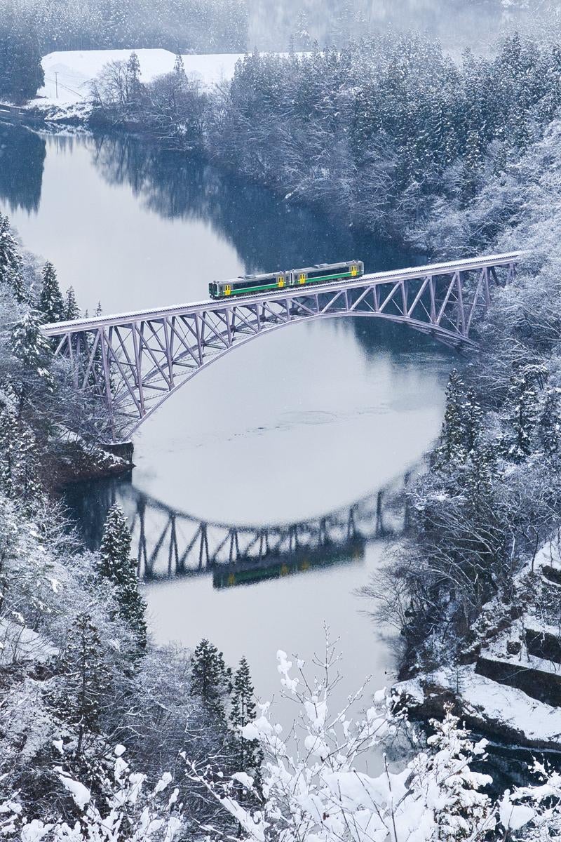 雪に覆われた第一只見川橋梁を走る列車の冬景色の写真