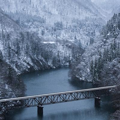 渓谷の川上に雪が積もる冬景色で見る只見川橋梁の写真