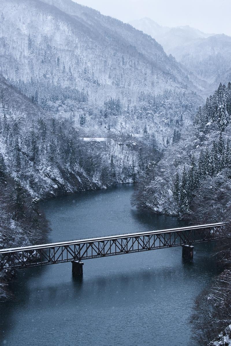 渓谷の川上に雪が積もる冬景色で見る只見川橋梁の写真