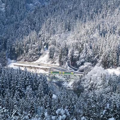 冬の山岳地帯を行き来する列車が通過する雪景色の鉄道橋梁の写真