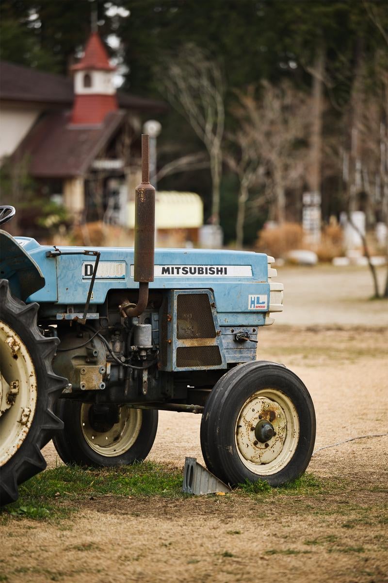 空色の古いミツビシトラクター。茶色い排気パイプと白いタイヤが見える
