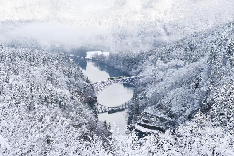 冬の第一只見川橋梁を渡る列車と雪景色の写真