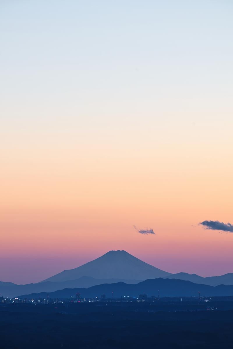 夕焼け空に浮かぶ富士山のシルエット、夜景の街明かりと共に映える情景の写真