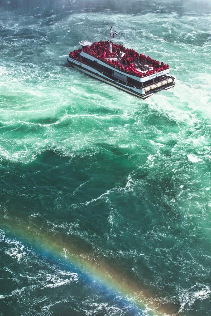 「流れの強いナイアガラ川の観光船と虹」の写真