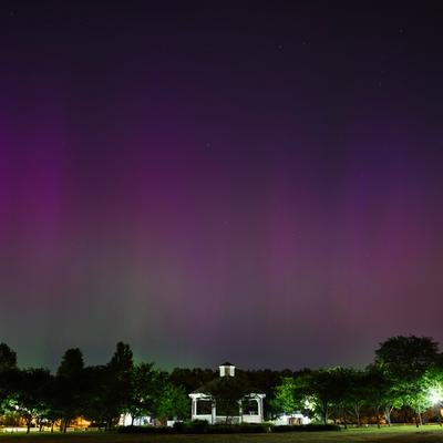 夜空に広がる紫色のオーロラと公園のガゼボの写真