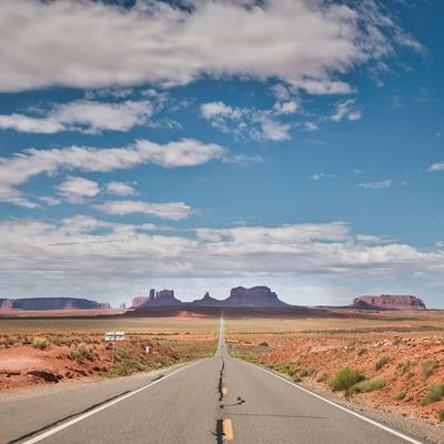 モニュメントバレーへ続く一直線の道路と壮大な砂漠風景の写真