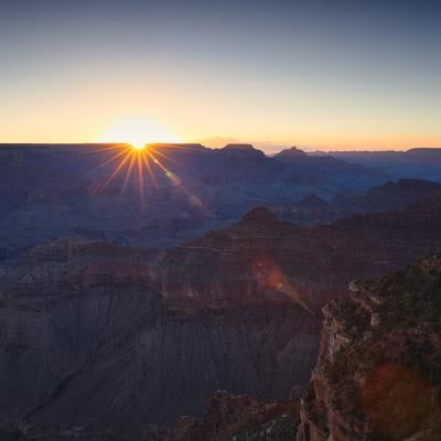 グランドキャニオンの渓谷を照らす朝日と光芒の写真