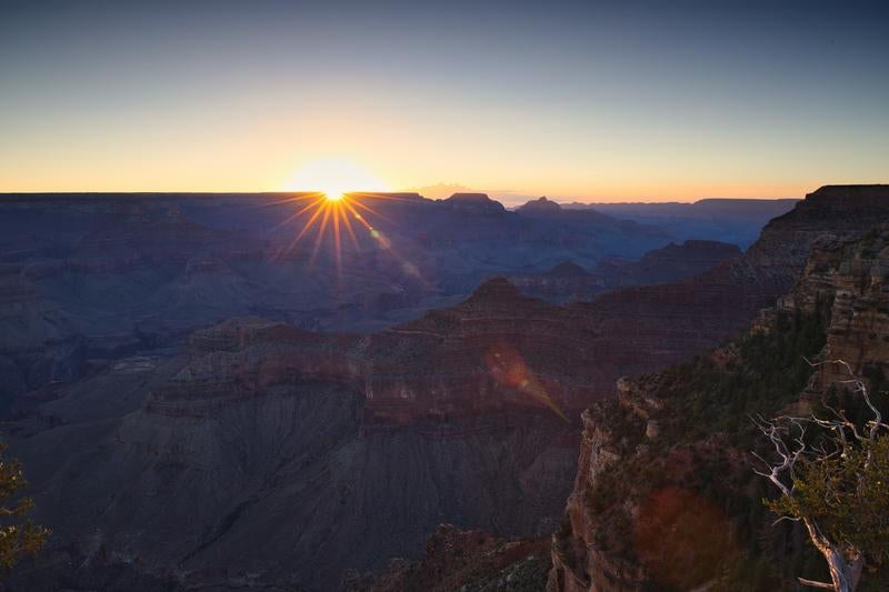 グランドキャニオンの渓谷を照らす朝日と光芒