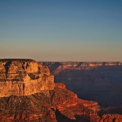 朝焼けに染まるグランドキャニオンの雄大な岩肌と峡谷の写真