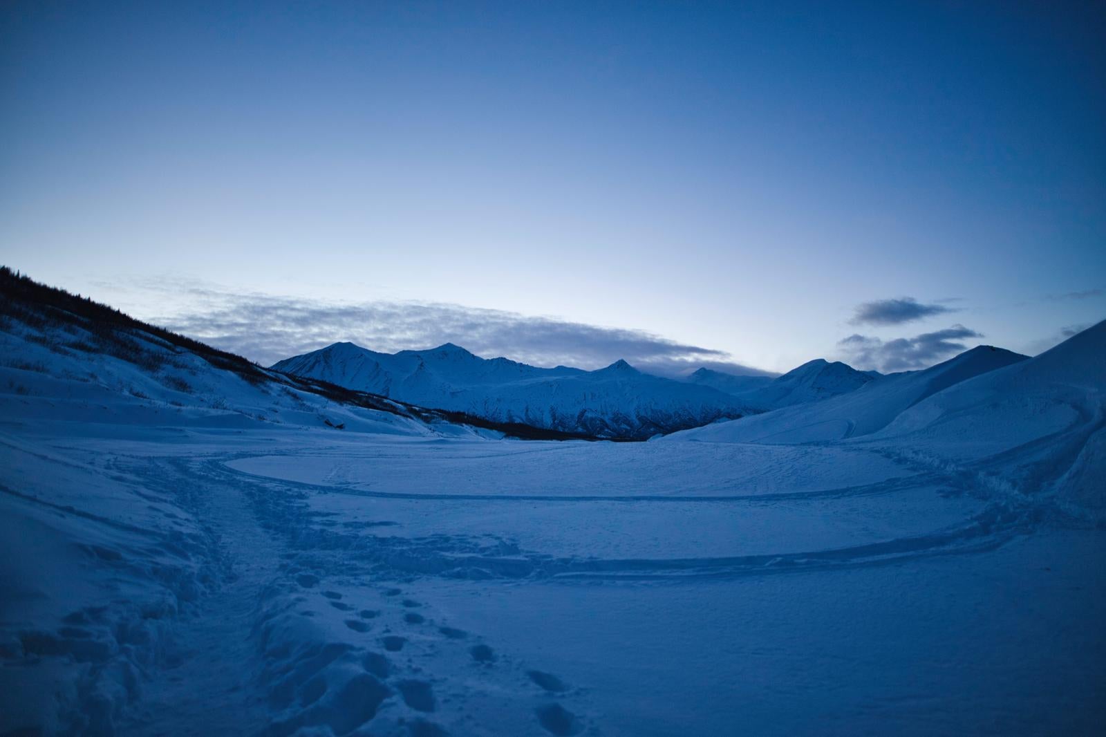 「雪原の足跡と雪に覆われた山々が広がり」の写真