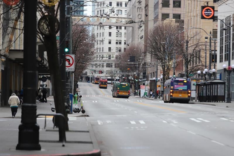 大通りに並ぶバスとシアトルの街並みの写真