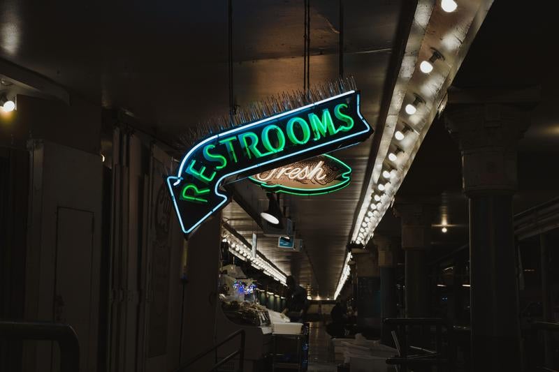 夜の市場で光る「RESTROOMS」のネオンサインの写真