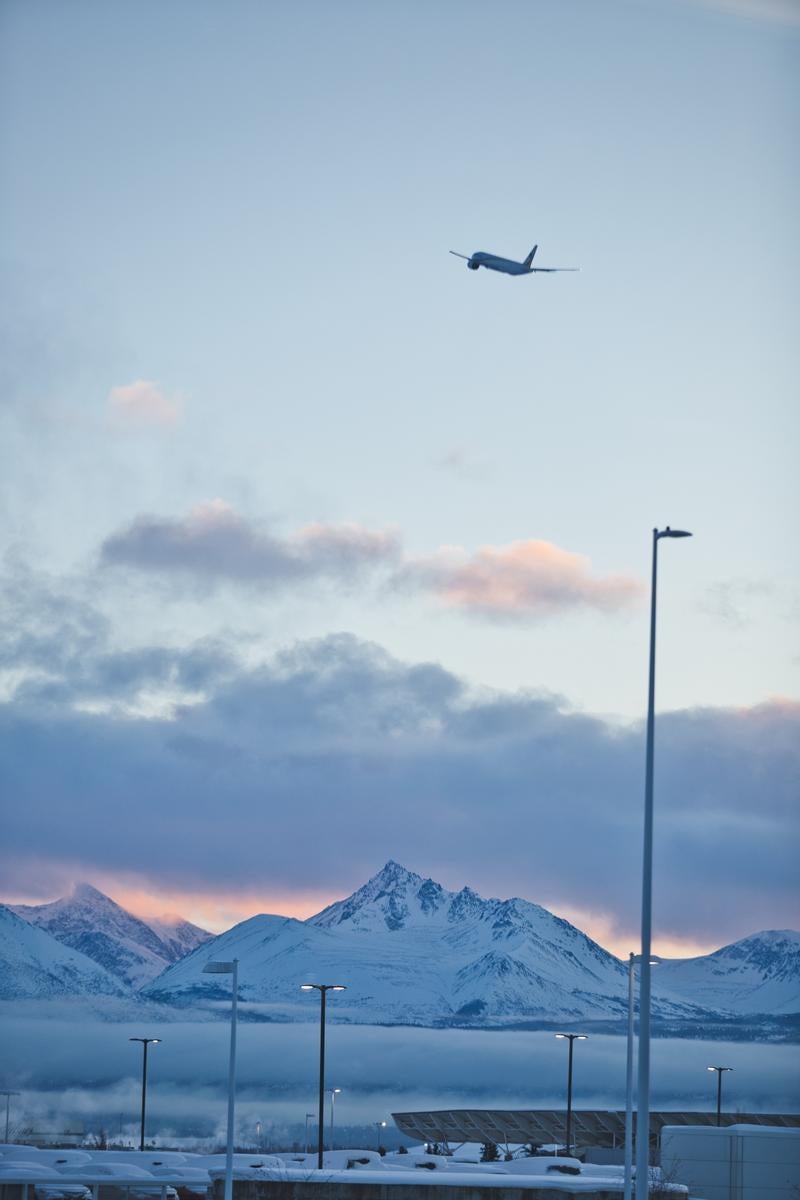 冬の夕暮れに映える雪山と飛行機の写真