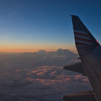 夕日に染まる雪山と飛行機の翼の美しい風景の写真