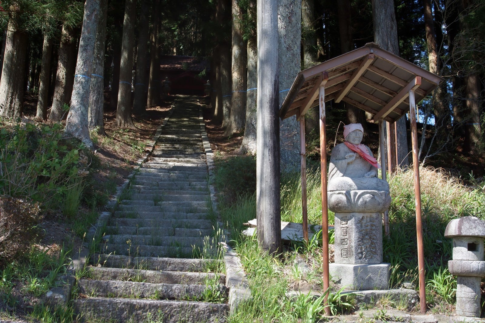 「山のお社に続く階段と入り口の石仏」の写真