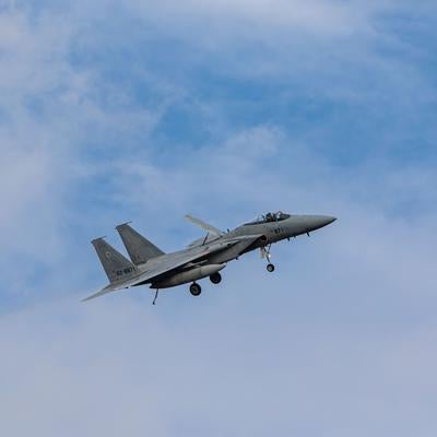 晴れた空に白い雲が浮かぶ中を飛行する航空自衛隊の戦闘機の写真