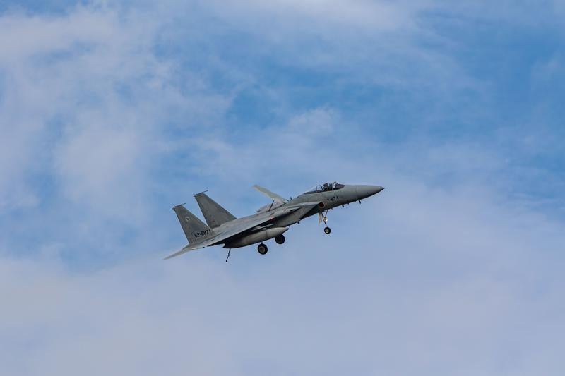 晴れた空に白い雲が浮かぶ中を飛行する航空自衛隊の戦闘機の写真