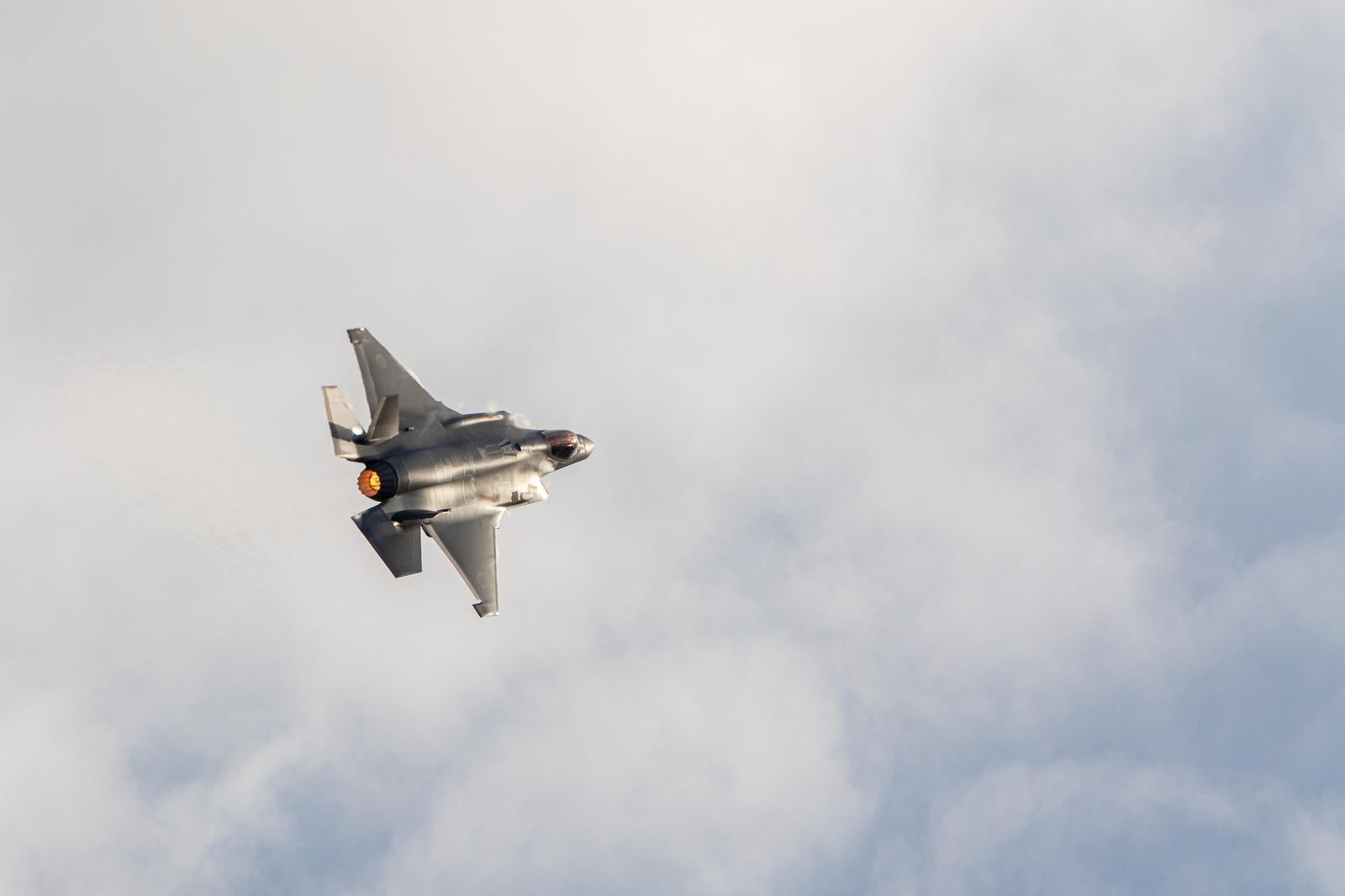 曇り空の中をアフターバーナーを噴射しながら飛行する航空自衛隊の戦闘機