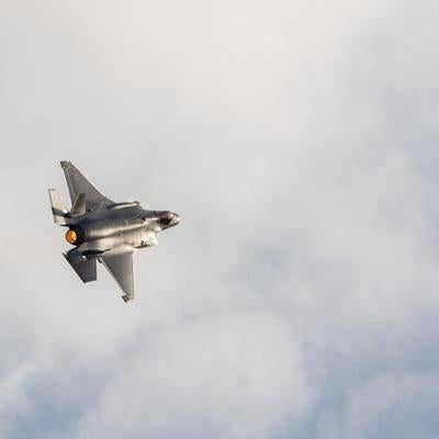 アフターバーナーを噴射して雲の中を飛行する戦闘機の写真