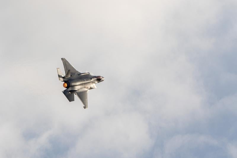 アフターバーナーを噴射して雲の中を飛行する戦闘機の写真