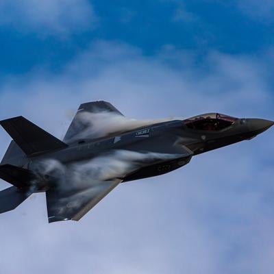 青空と雲の間を力強く飛行する航空自衛隊のステルス戦闘機F-35の写真