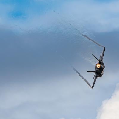 曇り空を背景に飛行する航空自衛隊の戦闘機の写真