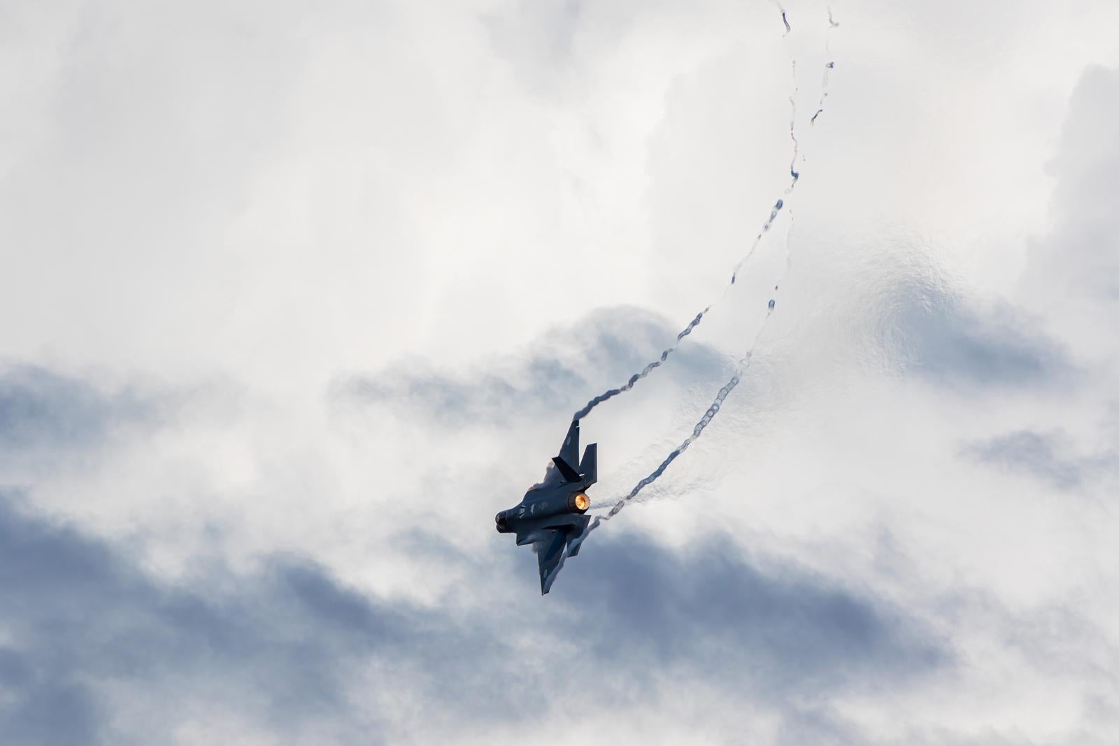 曇り空の中を飛行する航空自衛隊の戦闘機と飛行軌跡