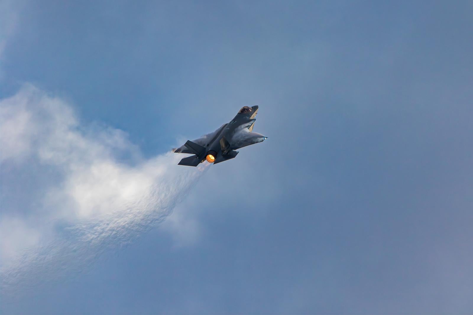 青空と雲の間を飛行する航空自衛隊のステルス戦闘機F-35