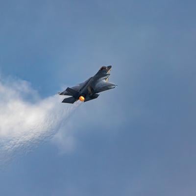 青空と雲の間を飛行する航空自衛隊のステルス戦闘機F-35の写真