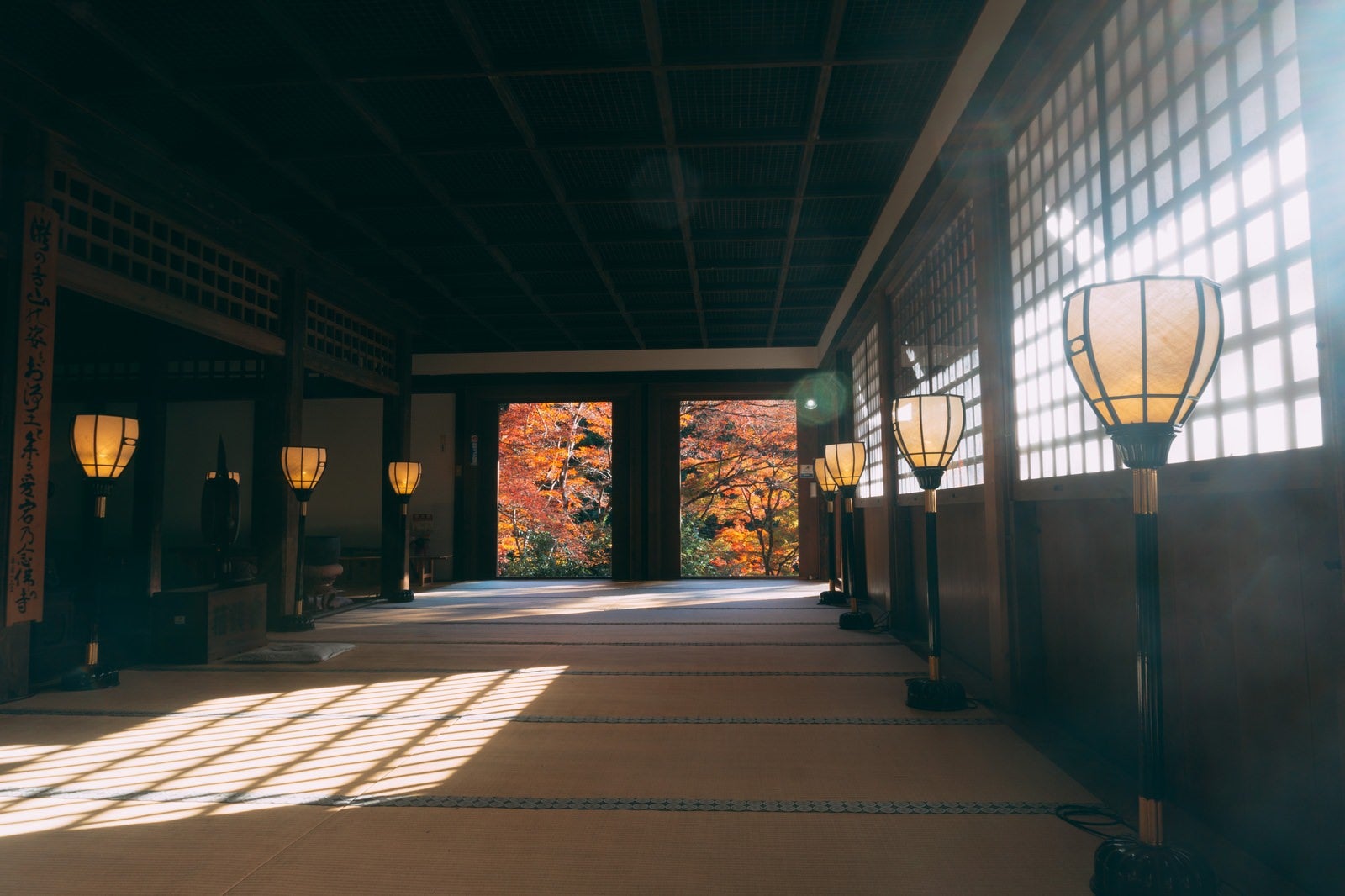 「障子越しの光が差し込む愛宕念仏寺本堂内と北側の扉の向うに見える紅葉」の写真