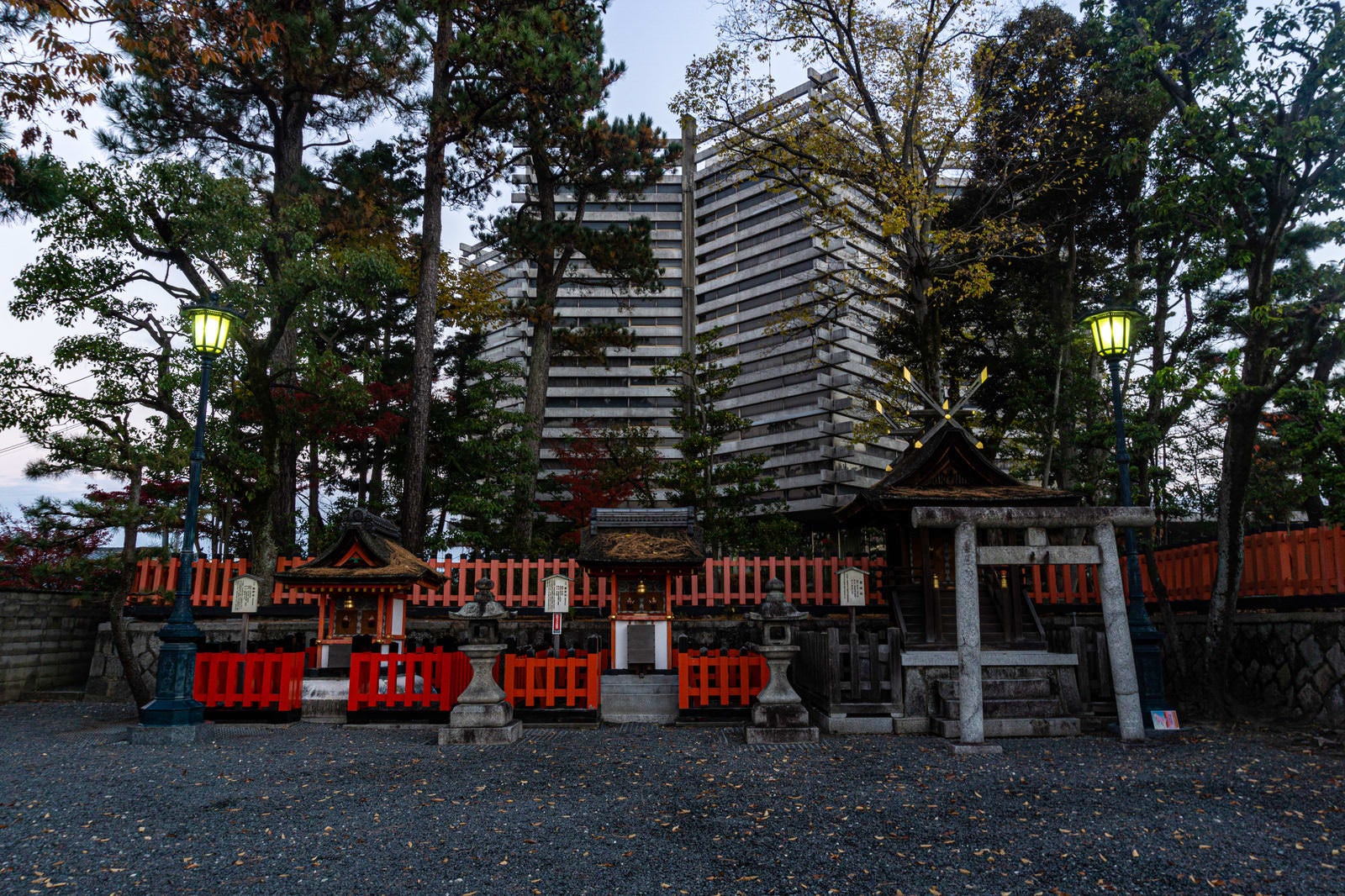 「伏見稲荷大社の一番鳥居と二番鳥居の間にある摂末社（せつまつしゃ）（向かって左から熊野社、藤尾社、霊魂社）と背後に建つ特徴的な儀式殿」の写真