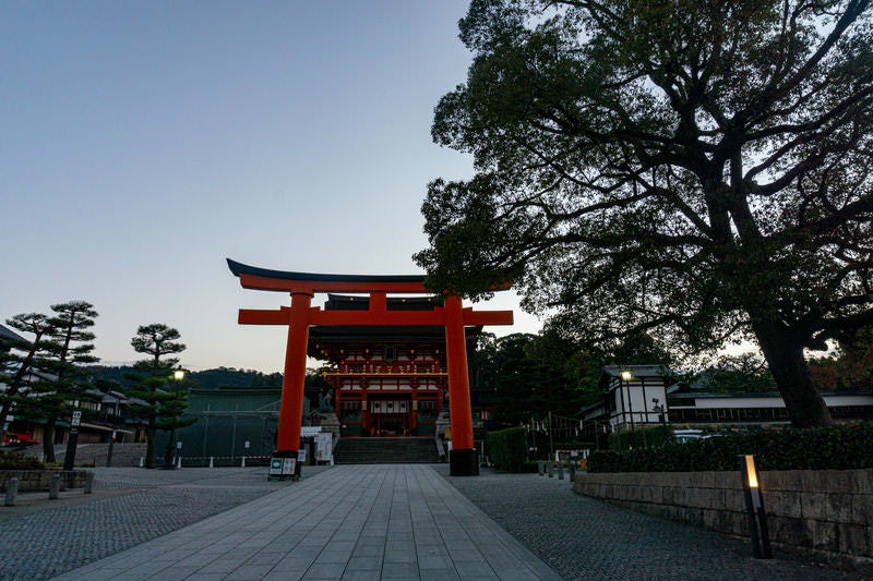 石畳の先、背後からの薄っすらとした朝の気配の中に建つ二番鳥居とその先に見える楼門の写真
