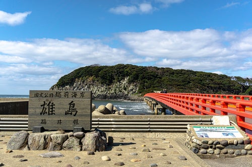 雄島を背景に建つ雄島の看板や説明図と雄島へと続く橋の写真