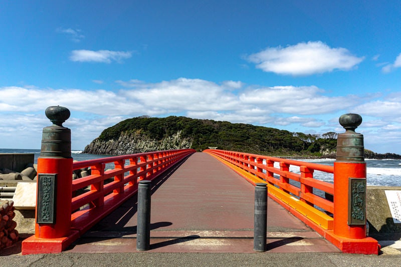 青い空と海に映える朱色が美しい雄島橋の写真