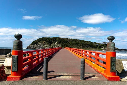 青い空と海に映える朱色が美しい雄島橋の写真