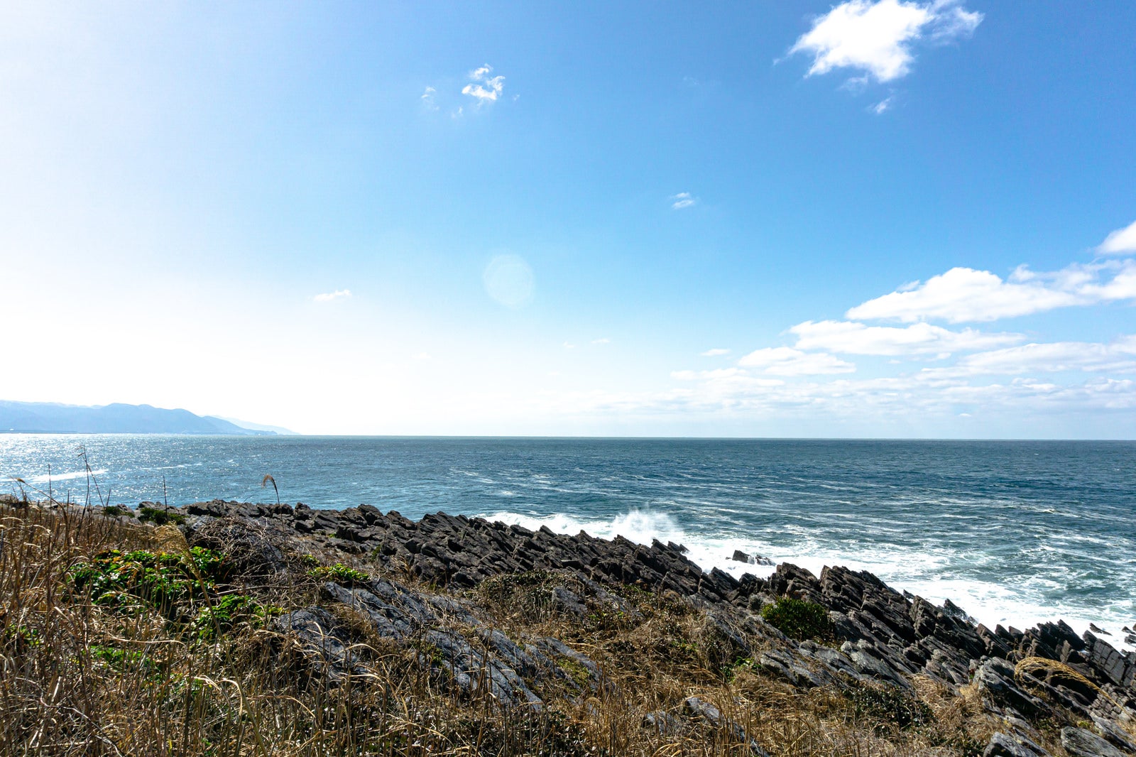 「島の遊歩道から見える雄島の西側に広がる板状節理に打ち寄せる波」の写真