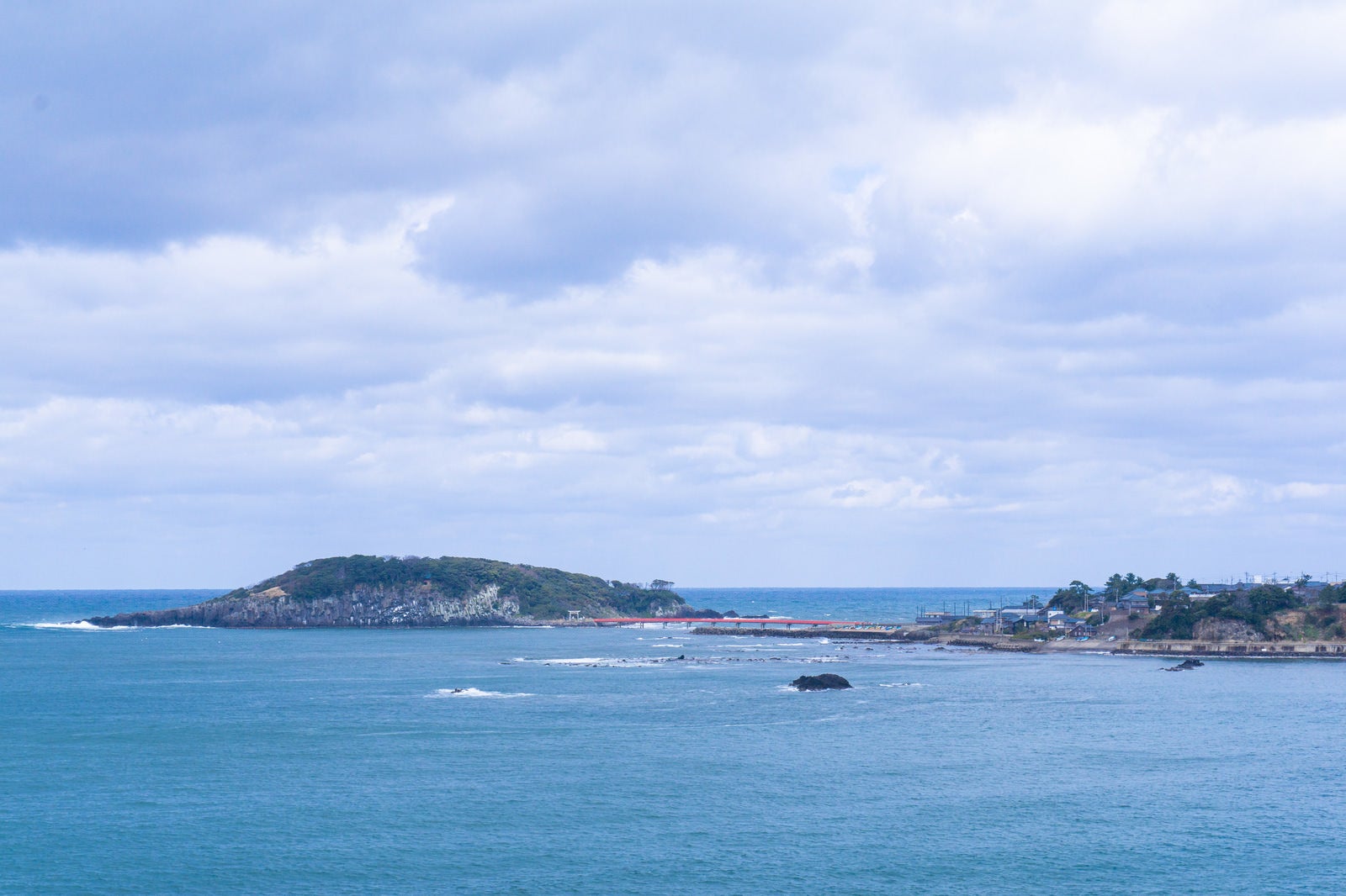 「東尋坊から見える海の神様の島と崇められる雄島と青い海にかかる赤い橋」の写真