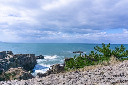 東尋坊の遊歩道から見る日本海と北西からの波に向かって進む軍艦や潜水艦に見える軍艦岩の写真