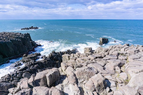 柱状節理の特徴がわかる柱を束ねたような岩場の上部に立ち日本海を眺めるの写真