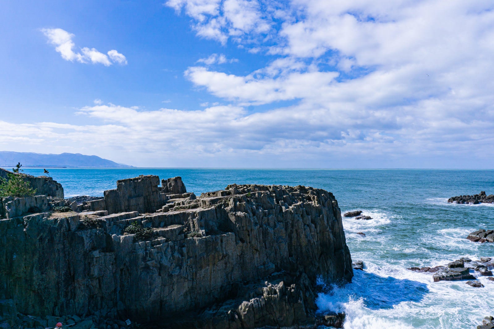 「千畳敷前にそそり立つ岩壁といくつもの岩にぶつかり白く沸き立つ海」の写真