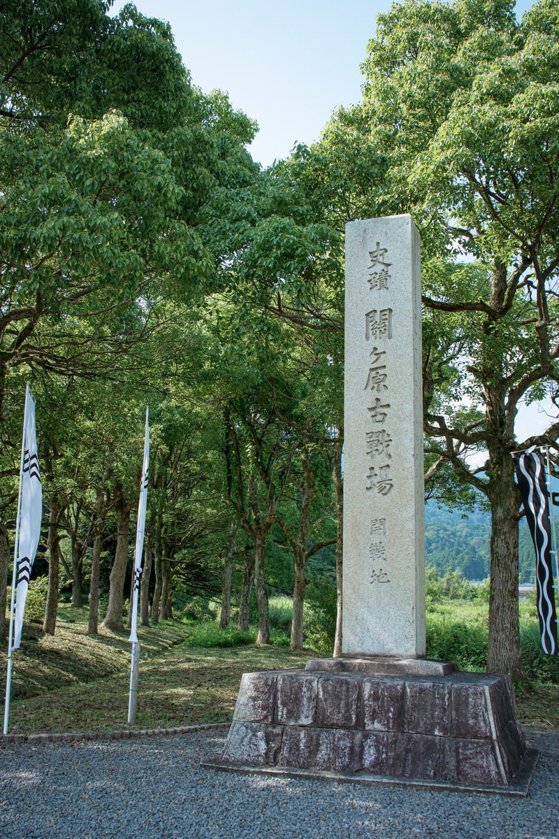 「緑豊かな木々を背景に建つ開戦地の石碑」の写真