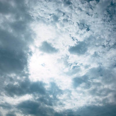 灰色の雲の合間から光が漏れる空の写真